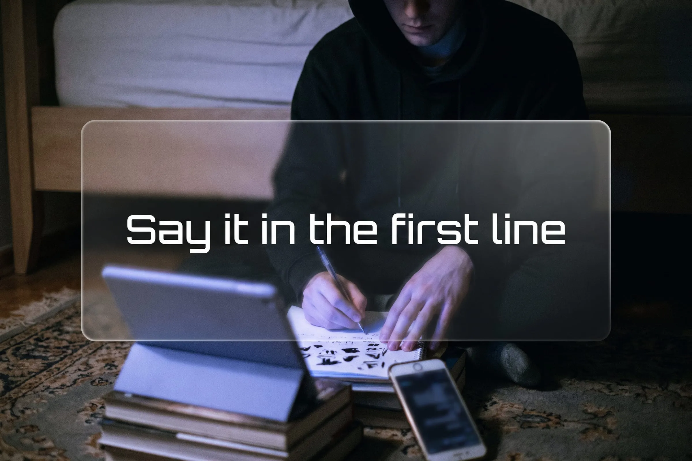 A person sits on the floor marking up a printed script page while a phone rests on a stack of books facing them.