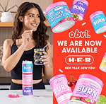 Woman smiling and holding a glass of water with Obvi collagen containers stacked nearby and text advertising Obvi availability at H-E-B.